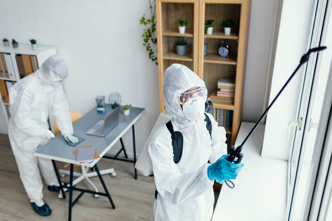 Pest control worker in a protective suit, goggles and mask, spraying with a long wand